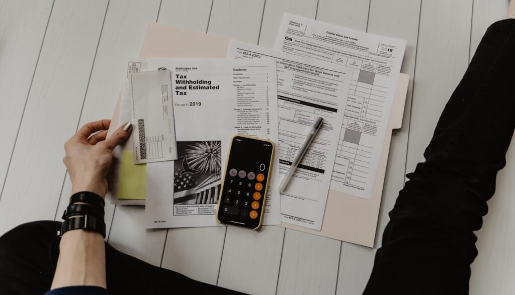 A professional reviewing tax documents at a desk with a calculator and phone, top-down view.